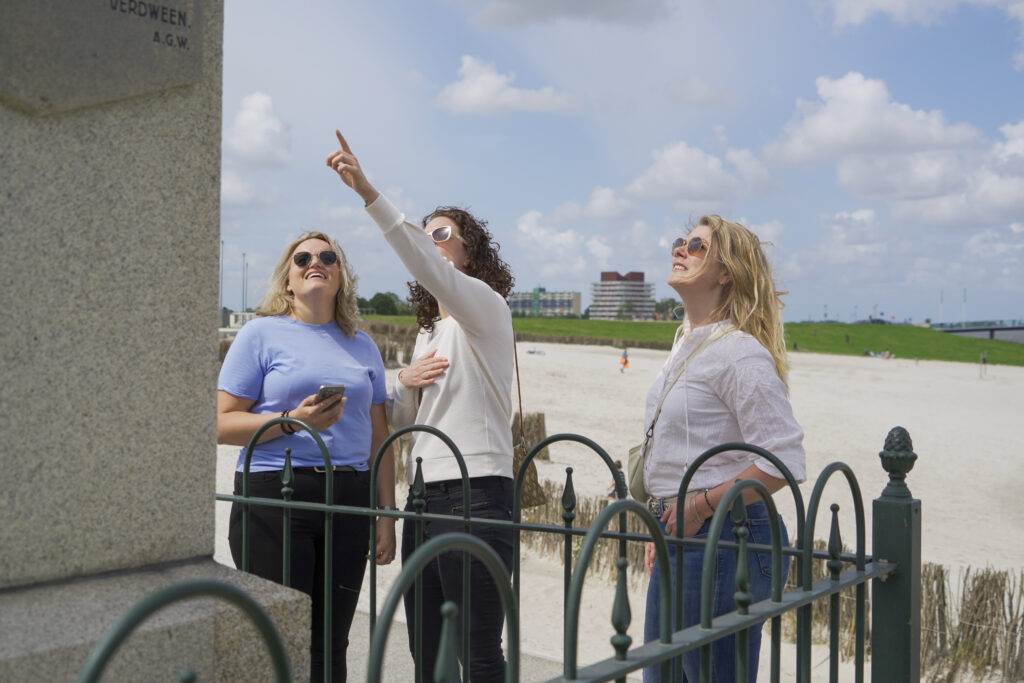 3 vrouwen staan bij het strand van Delfzijl. een wijst omhoog.